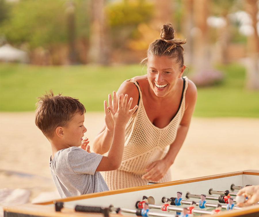 Une maman et son enfant jouent au babyfoot dehors